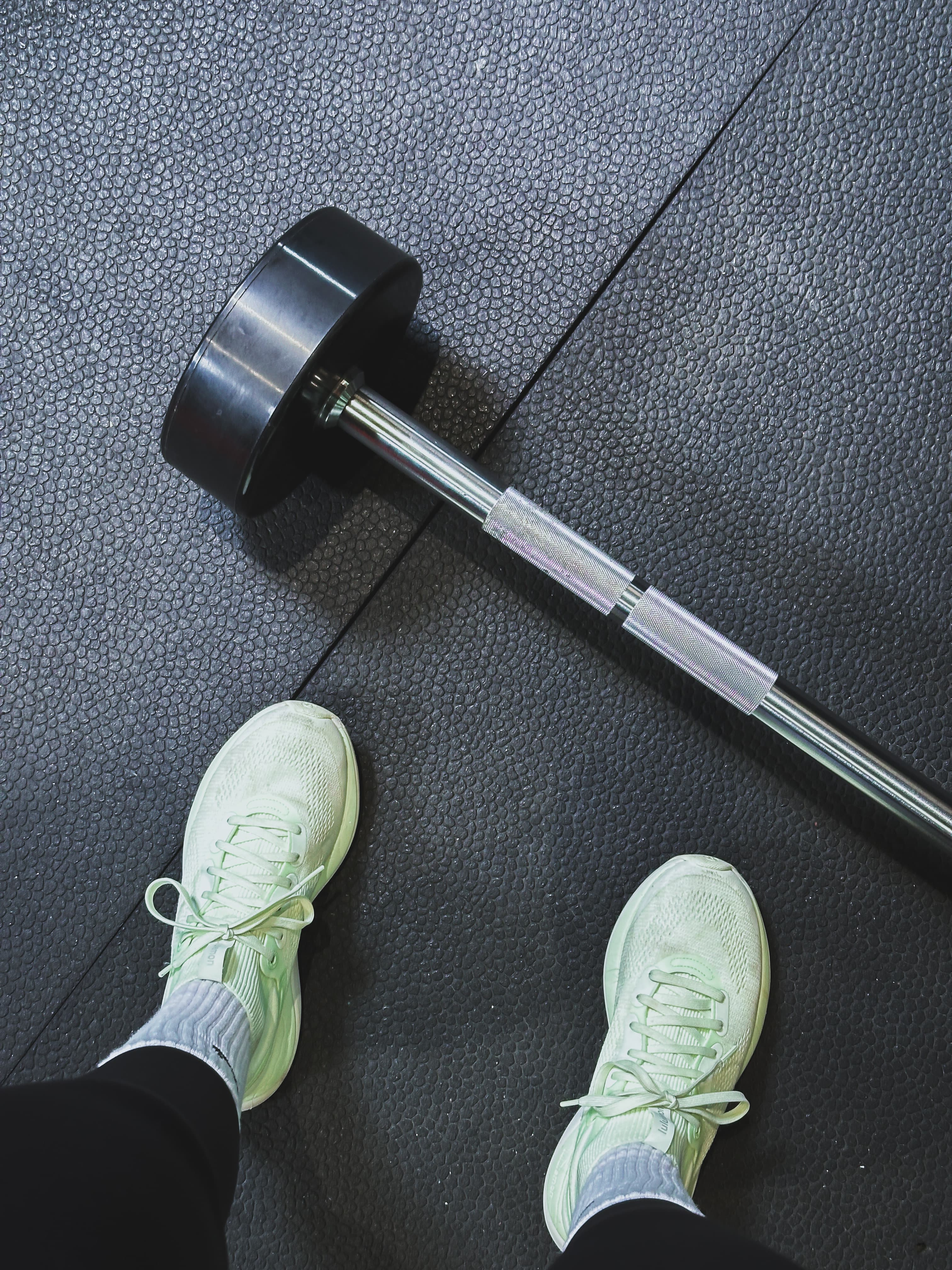 Training shoes and a barbell on a gym floor